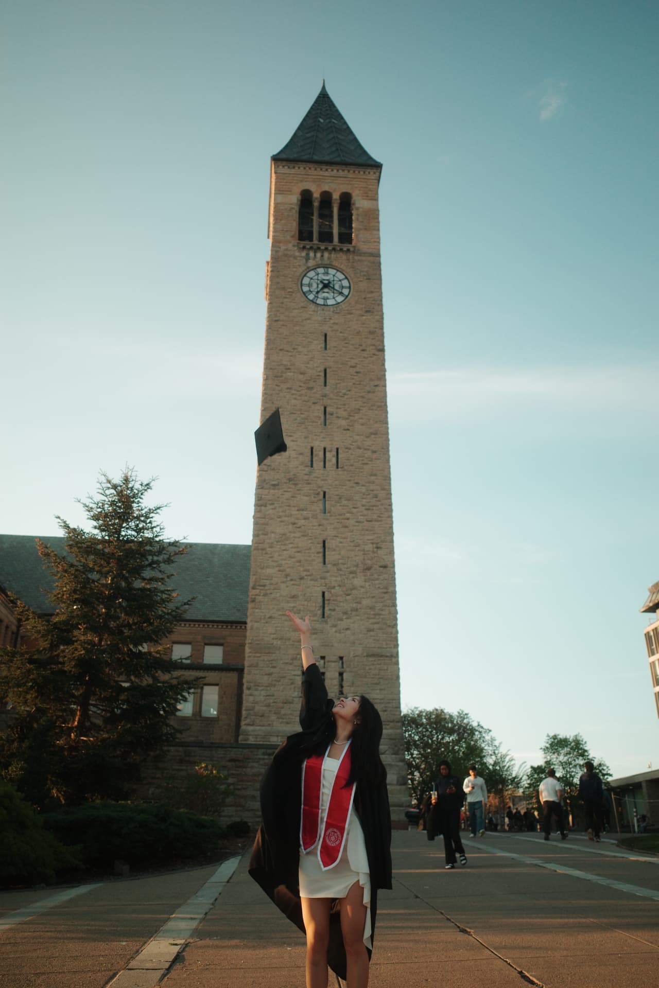Josephine in front of the Cornell clock tower, tossing a graduation cap